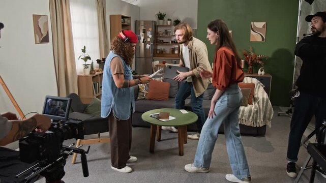 Caucasian film crew and actors discussing script during video shoot on set. Suitable for filmmaking tutorials, media production ads, and behind scenes content