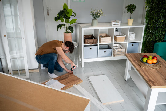 Young man assembling flat pack furniture at home