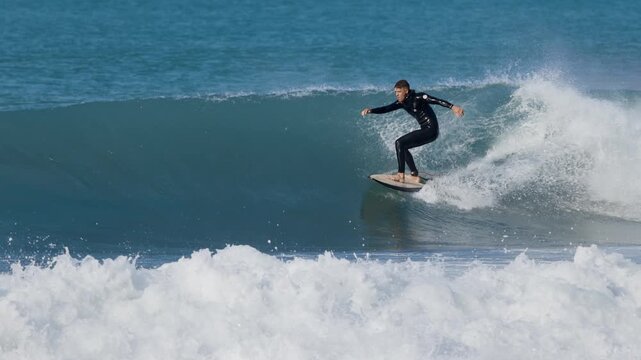 Surfer man riding on surfboard on ocean wave. Surfing slow motion