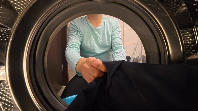Hands Unloading Dark Clothes and Towel from Washing Machine