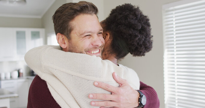Image of happy diverse couple hugging in kitchen