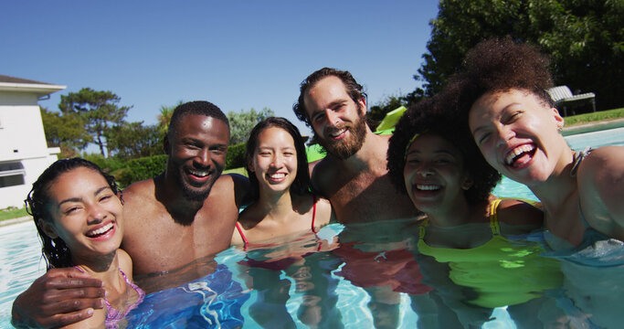 Diverse group of friends having fun taking a selfie in swimming pool