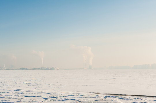 Frozen winter snow field landscape. Industrial factory plant smoke pollution