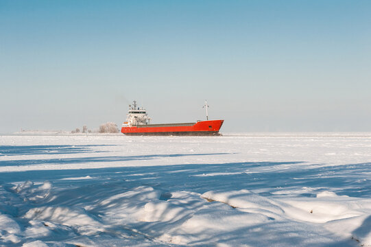 Winter shipping. Big cargo ship in frozen sea fairway