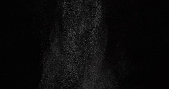 Close-up of dust particles rising from below against a black background. Can be used as overlay elements for design projects. 