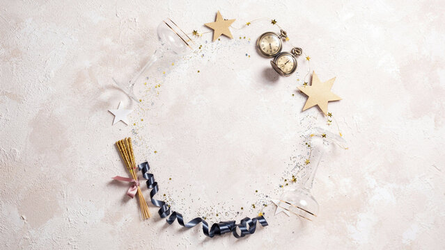 Elegant New Year's Eve Flat Lay with Crystal Champagne Glasses, Vintage Brass Pocket Watch Near Midnight, Gold Star Confetti and Navy Ribbon on Blush Textured Background