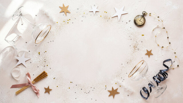 Luxury New Year Party Background with Gold Foil Paper Stars, Curled Midnight Blue Streamers, Champagne Confetti and Crystal Drinkware Arranged Around an Open Blush Center