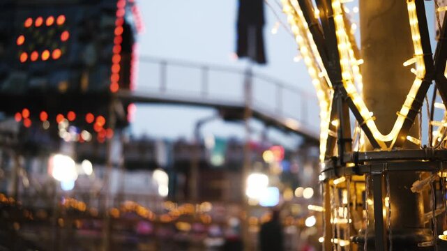 Glowing Christmas Garlands Light Up The Amusement Park At Night Against A Blurred Colorful Kids Roller Coaster Background At The Fair