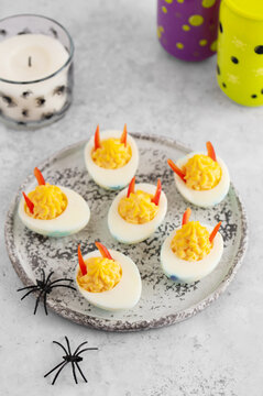 Halloween devil deviled eggs with pepper horns and plastic spiders