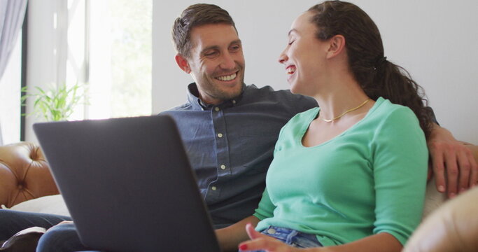 A young caucasian couple talking and paying their bills using a laptop