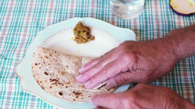 Cooked roti placed on a plate, a piece is broken and served with mango pickle