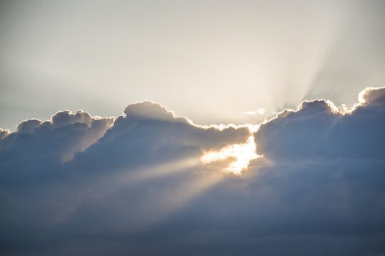Sunbeams shining through clouds high in the sky during the evening, just before sunset&mdash;a warm, atmospheric landscape for a background
