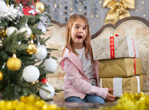 Little girl holding gifts in Christmas interior