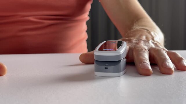 Close up of fingertip in sensor clip of oximeter. Hands with gadget detail and nails. Compact portable device for pulsometer use..