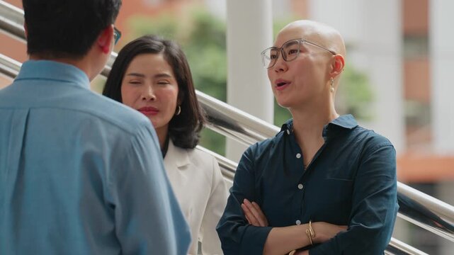 Three people converse on a modern staircase. One person laughs warmly, showing joy and engagement. Another listens attentively, conveying focus