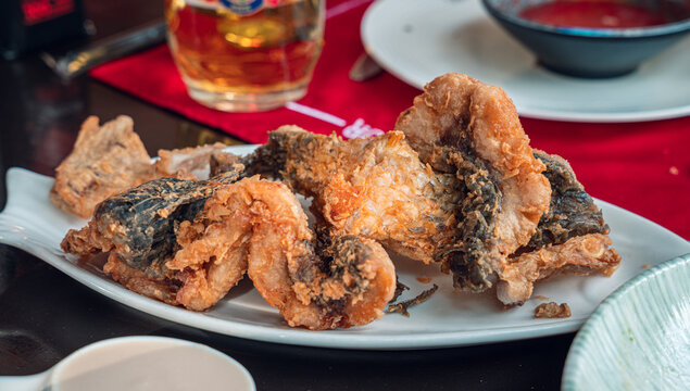 A plate of crispy fried fish is served, showcasing its golden-brown texture. The dish is accompanied by a beverage, suggesting a delightful dining experience.