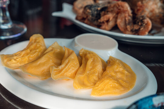 A plate of golden dumplings is elegantly presented with a side of creamy dipping sauce. The dumpling dish is a perfect blend of flavors, making it an enticing meal.