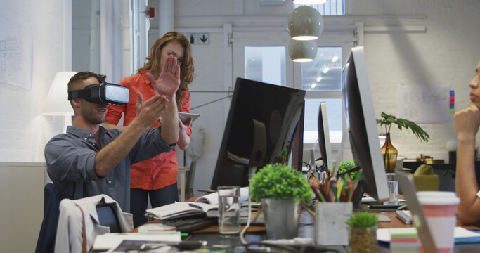Two professionals collaborate in a high-tech office, utilizing VR and digital tools.