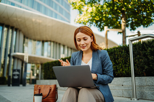 Businesswoman working on a laptop outside a modern office building