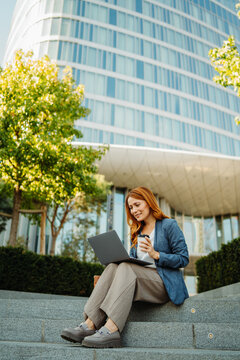 Businesswoman working remotely outside a modern office building