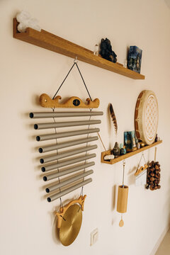 Wall display of wooden shelves, hanging wind chimes, woven decoration, carved mask, and small ornaments in a cozy interior
