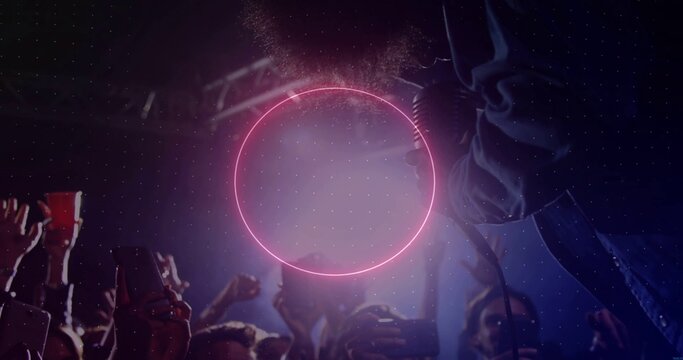 Pulsing neon pink ring above crowd with smartphones at club, with singer in denim reaching mic