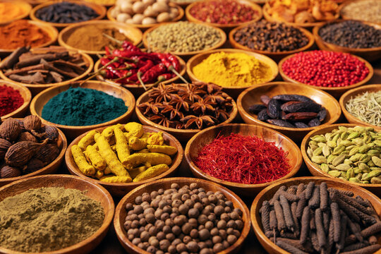 various spices and herbs in wooden bowls, colorful spice powders and seeds