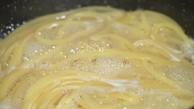 Raw spaghetti is being cooked in boiling water in a kitchen pot. Healthy Italian Food and Cooking concepts.