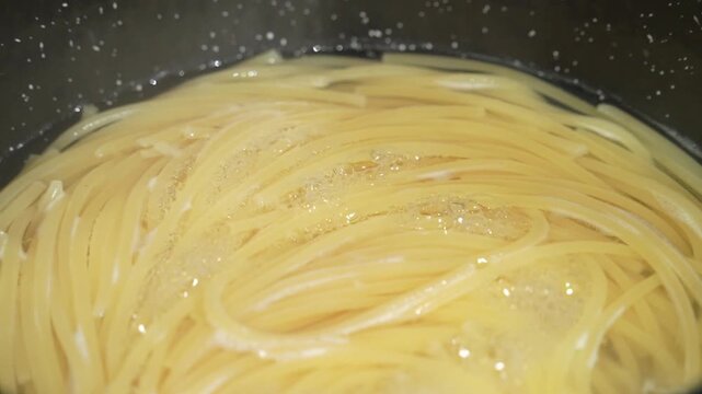 Raw spaghetti is being cooked in boiling water in a kitchen pot. Healthy Italian Food and Cooking concepts.