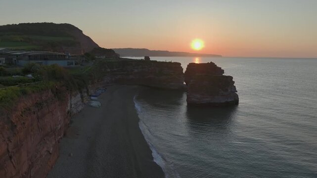 Sunrise over red coastal cliffs and sea stacks at Ladram Bay, Devon, England