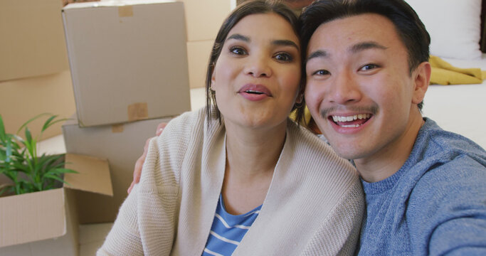 Image of happy diverse couple taking selfie in new house