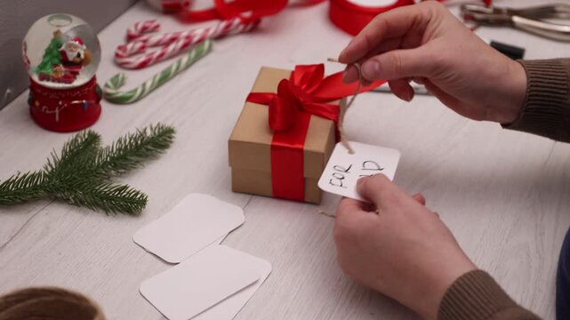 Handwritten gift tag for dad being attached to a beige gift box with red ribbon