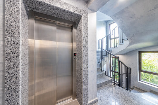 Modern Apartment Building Stairwell with Stainless Steel Elevator, Granite Walls, and Spiral Staircase Interior