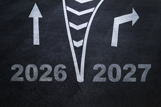 Asphalt road markings with arrows and numbers 2026 and 2027 showing direction split, representing transition, future planning, choice, business strategy, goals, new year, decision, and opportunity