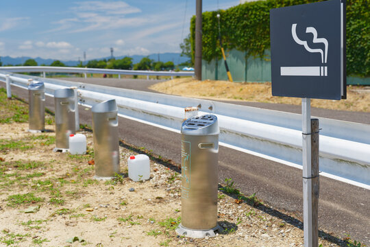Outdoor smoking area with cigarette sign and metal ashtrays