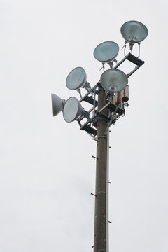 Outdoor floodlights against a pale sky with copy space