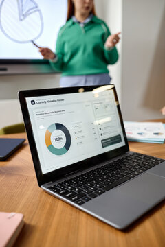 Vertical shot of young adult woman presenting financial data on screen in coworking office. Visual represents corporate analytics for fintech marketing