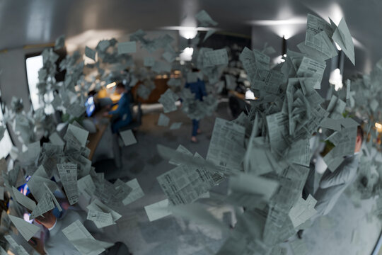 Corporate office chaos with flying papers and business team in modern workspace