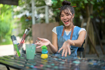 Joyful young artist sharing creativity at an outdoor art table © Wasana