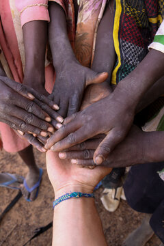 Hands of children stacked together over a white hand, Sahel Region, Gorom-Gorom, Burkina Faso