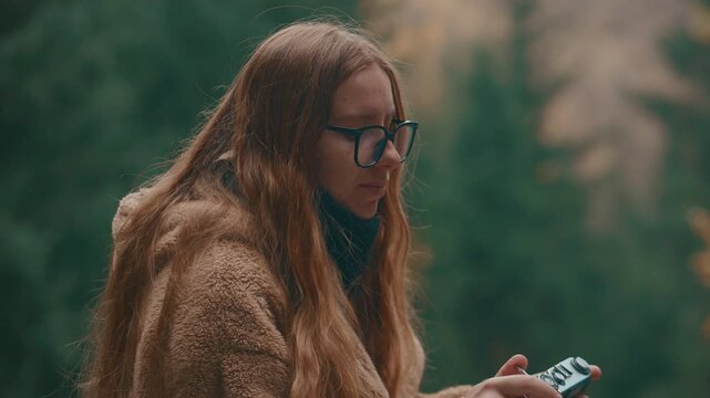 Woman photographer captures scenic forest landscape with film camera outdoors