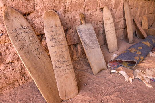 Row of wooden boards with Arabic verses leaning against a mud wall in a Koranic school, Sahel Region, Bani, Burkina Faso