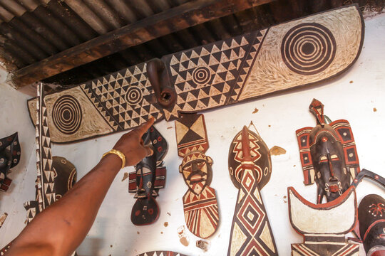 Hand pointing at painted wooden masks of the Bwa tribe on a wall, Hauts-Bassins Region, Bobo Dioulasso, Burkina Faso