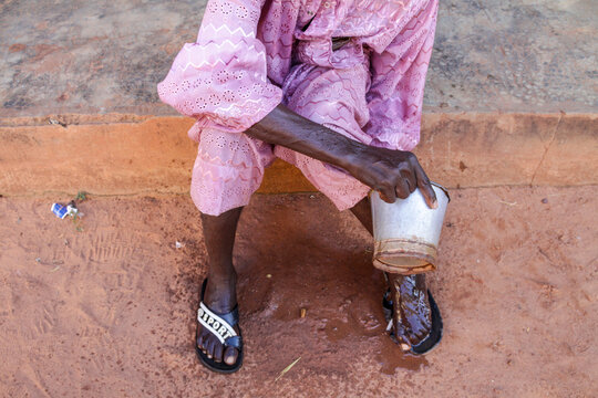Person in pink embroidered outfit holding a kettle during ablutions, Hauts-Bassins Region, Bobo Dioulasso, Burkina Faso