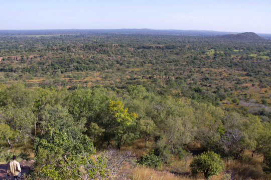 Person standing on a hill above a vast green savanna, Cascades Region, Niansogoni, Burkina Faso