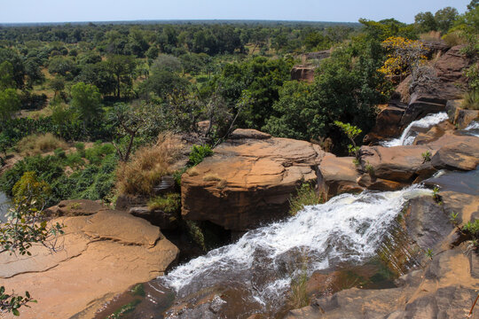 Karfiguela Falls cascading over sandstone rocks above a green wooded valley, Cascades Region, Banfora, Burkina Faso