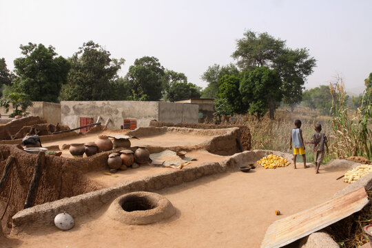 Two children of the Lobi tribe walking on the terrace roof of a soukala house, Sud-Ouest Region, Gaoua, Burkina Faso
