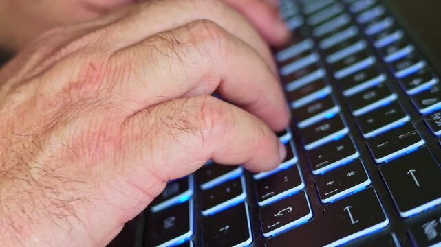 Close-up video frame of hands typing on a modern laptop keyboard with blue backlighting during remote work and digital tasks.