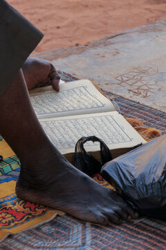Man reading the Quran with his bare foot on a prayer mat, Hauts-Bassins Region, Bobo Dioulasso, Burkina Faso