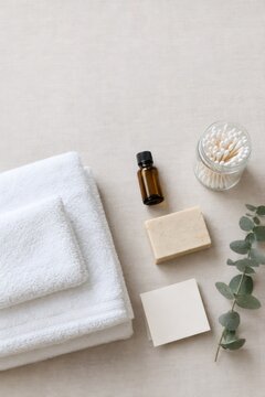 Skincare and bathing essentials arranged on a neutral surface with towel, soap and cotton swabs. Natural beauty and personal care routine. Spa wellness and self care concept.